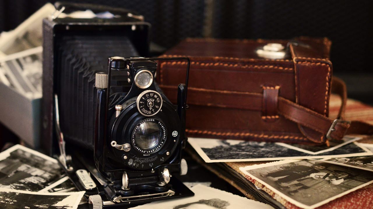En analog bälgkamera omgiven av svartvita fotografier
