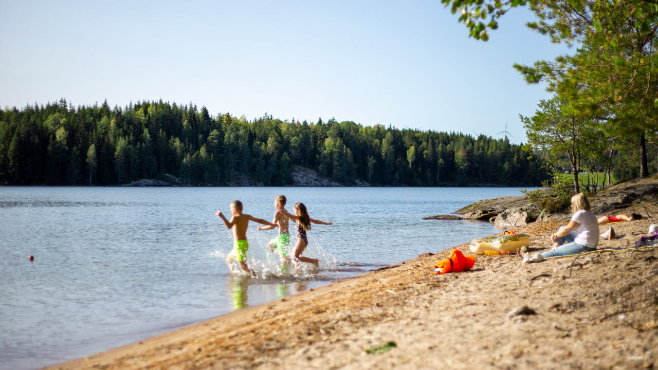 Tre barn som springer ut i vattnet