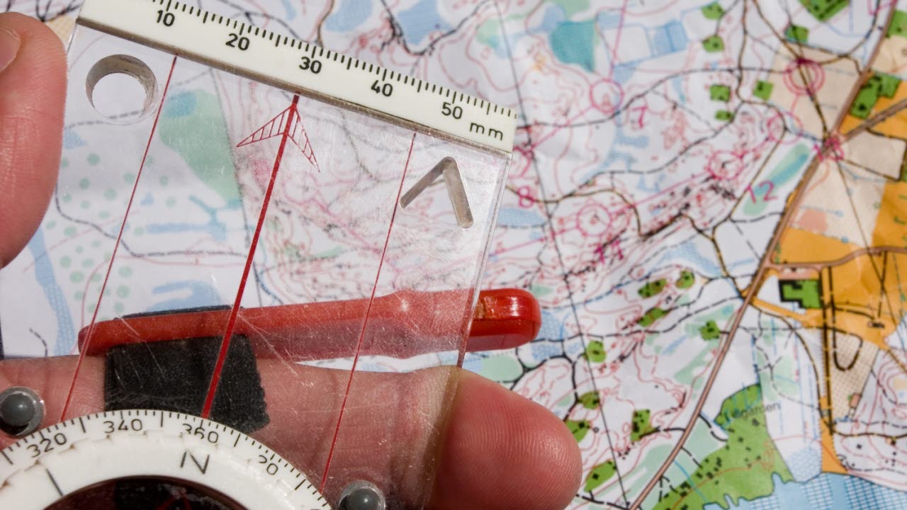 En hand håller i en kompass ovanför en karta.