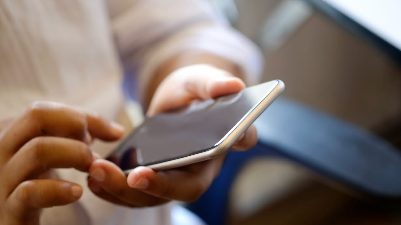 En smartphone och en hand som vilar över den