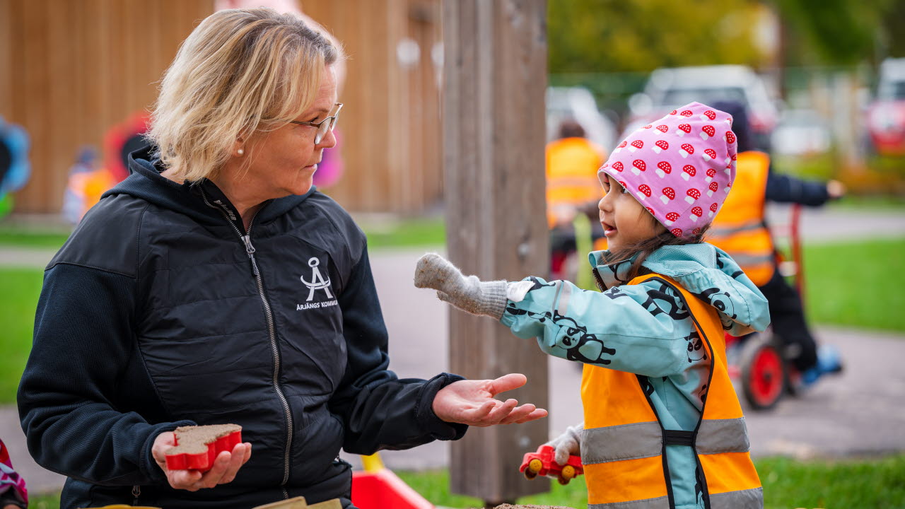 Pedagog och förskolebarn i utelek