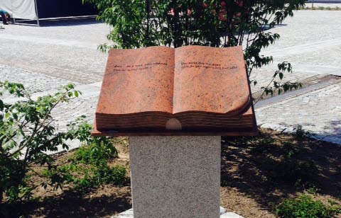En bok i sten som ligger uppslagen på en pelare.