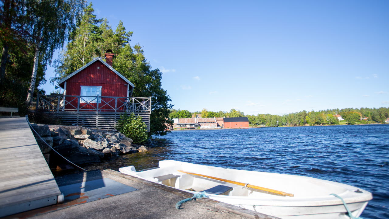 En fritidsbåt kör över en sjö. Solen håller på att gå ned vid horisonten.