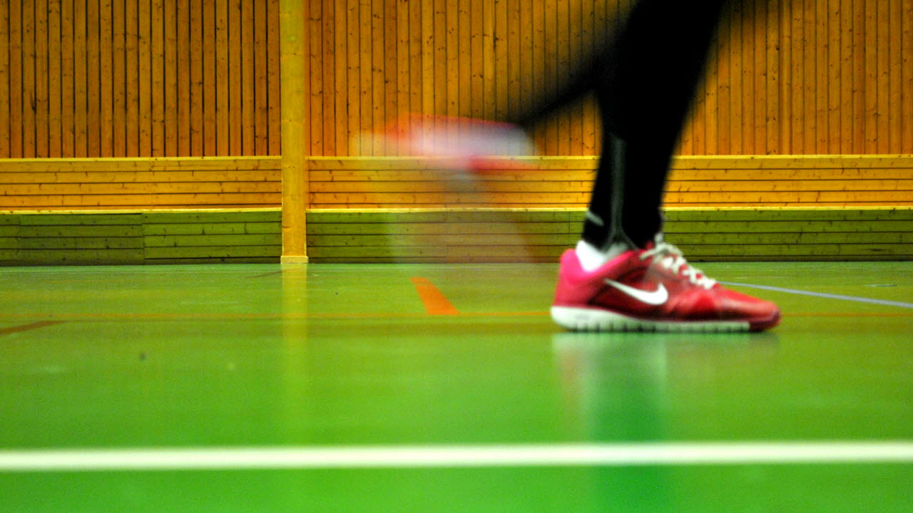 Ett par fötter i gympaskor som springer inomhus i en sporthall.
