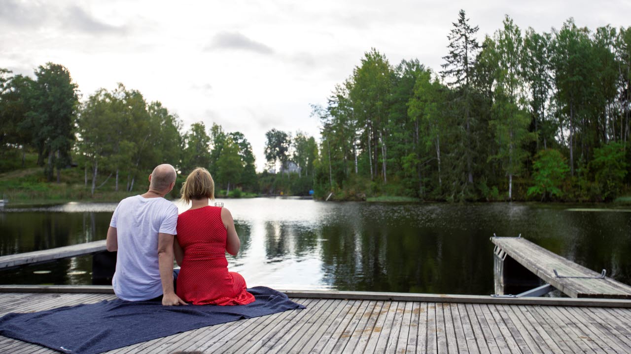 Ett par står vid strandkant och tittar ut över en sjö i Årjängs kommun