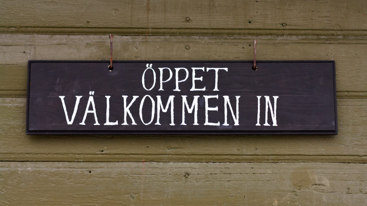En träskylt med målad text: Öppet välkommen in