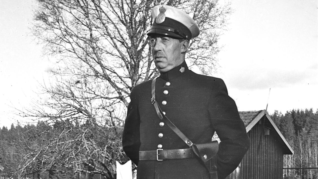 Svartvitt fotografi på en polisman i en gammaldags uniform. Fotograf: John Brander