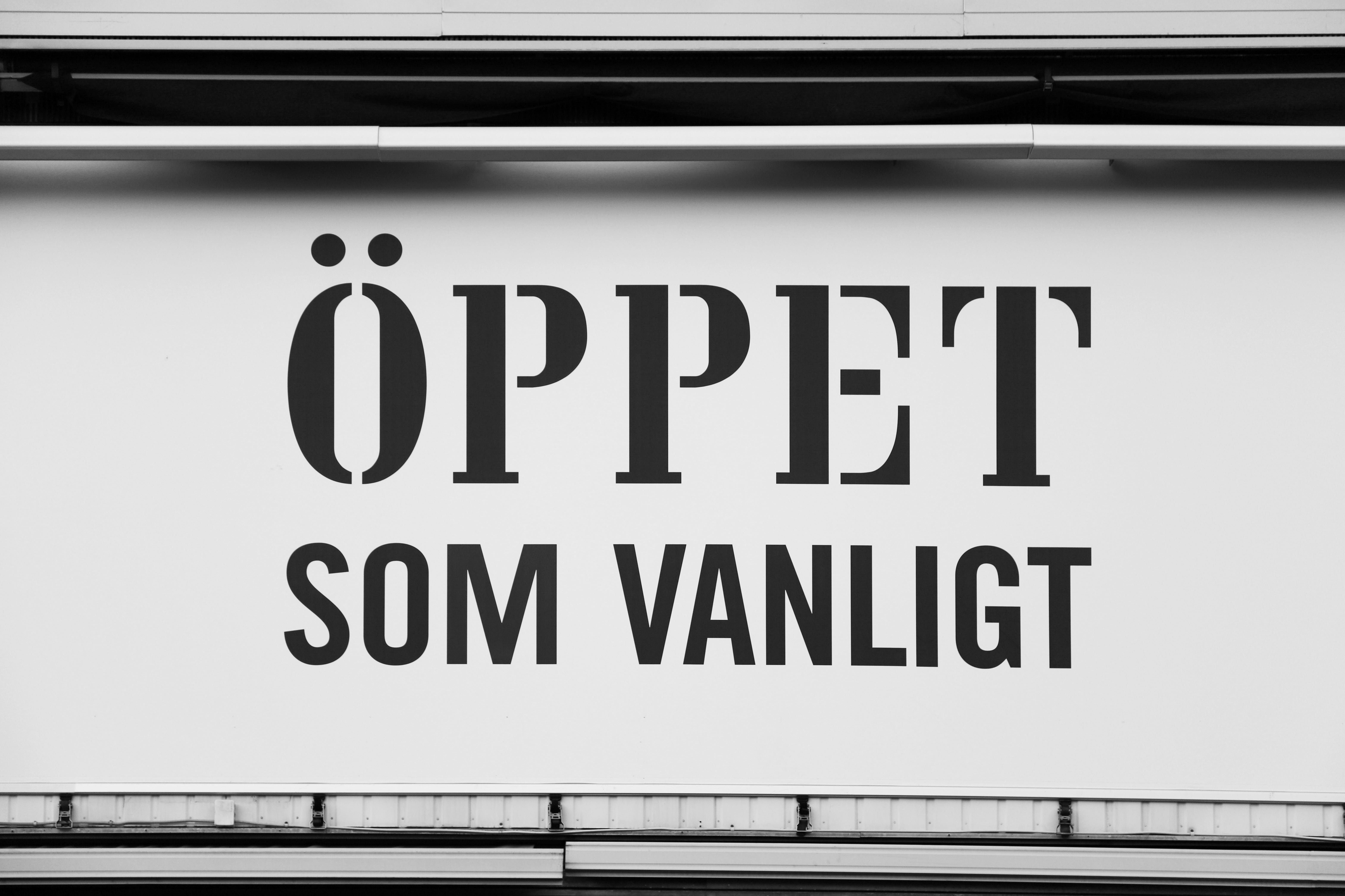 Skylt på vägg med text: Öppet som vanligt